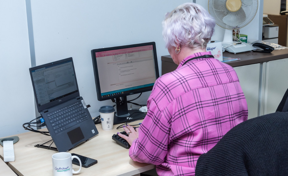 A Southdown colleague is sat at a desk looking at two computer screens in front of them.