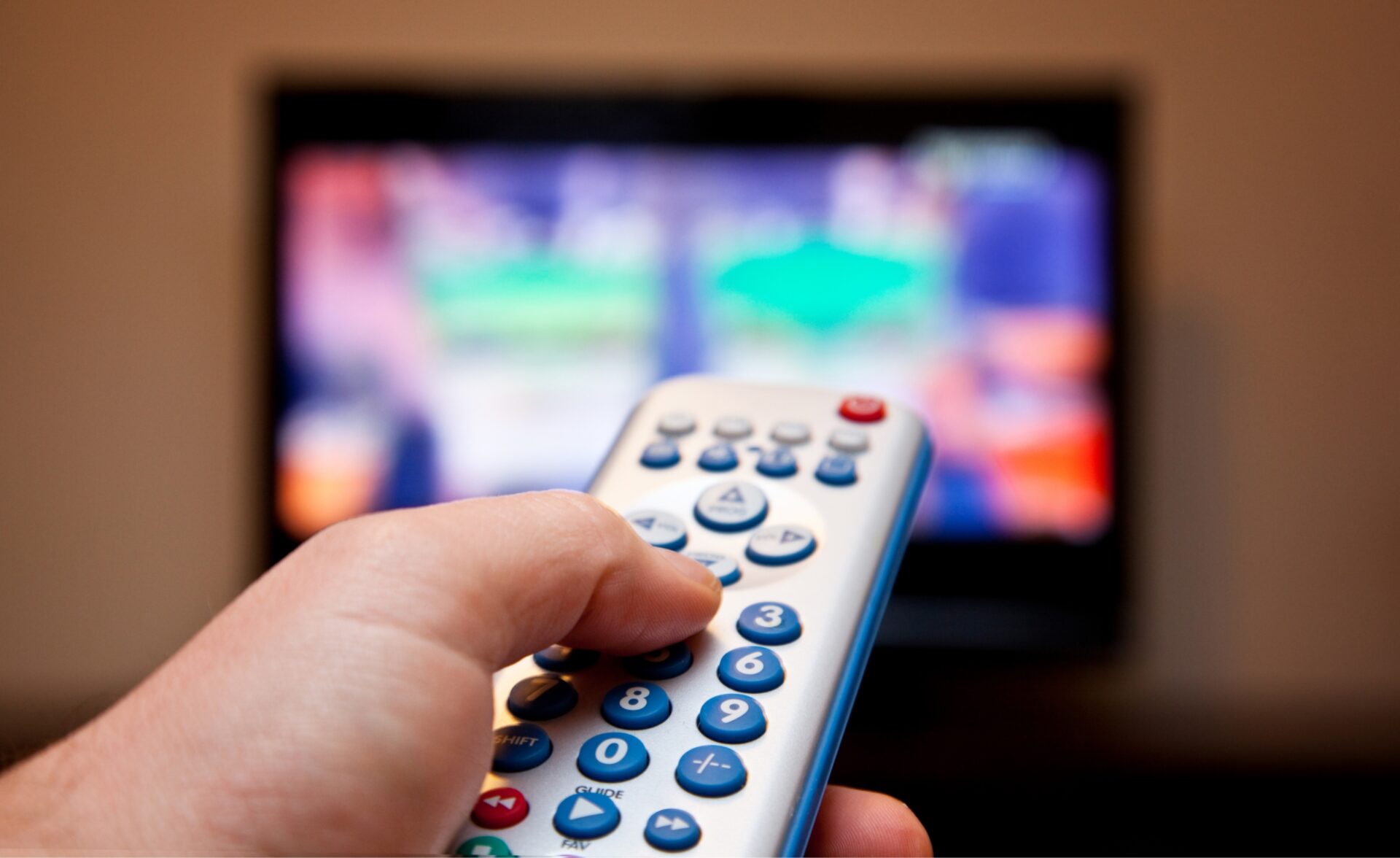 A photo of somebody holding a remote in front of a TV.