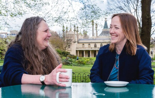 A Southdown employee and client are sitting at a cafe chatting outside Brighton Pavillion.