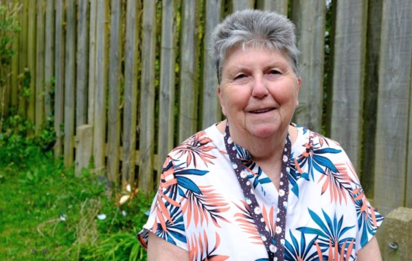 A Southdown employee is sat in the garden and is smiling at the camera.