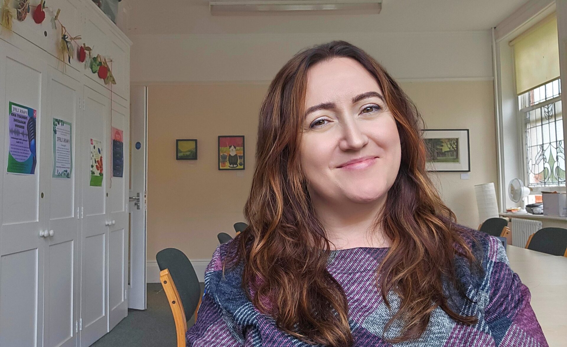 Southdown's Client and Tenant Lead is smiling at the camera, whilst sitting in a room at our Preston Park Wellbeing Hub Service.