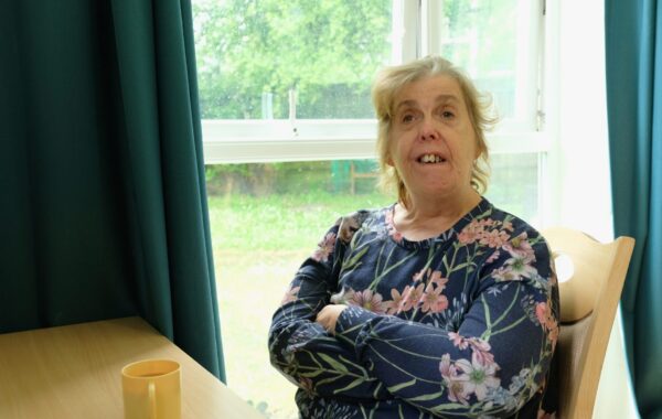 A Southdown client is sitting at a table and is looking at the camera.