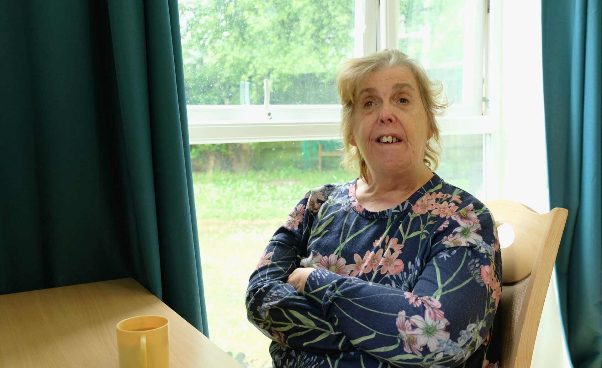 A Southdown client is sitting at a table and is looking at the camera.