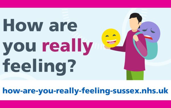 A graphic with the text 'How are you really feeling?' displayed in bold, with the word 'really' highlighted in pink. On the right, an illustration shows a person holding a smiling emoji mask, while a sad face is visible on a backpack they are wearing. Below, the campaign website URL 'how-are-you-really-feeling-sussex.nhs.uk' is prominently displayed on a white background with pink borders.